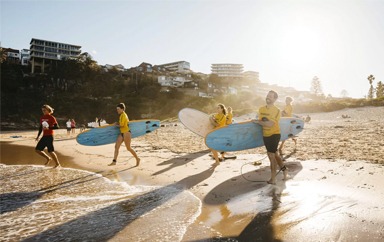 Adults enjoying a learn to surf experience with Manly Surf School at Freshwater Beach.